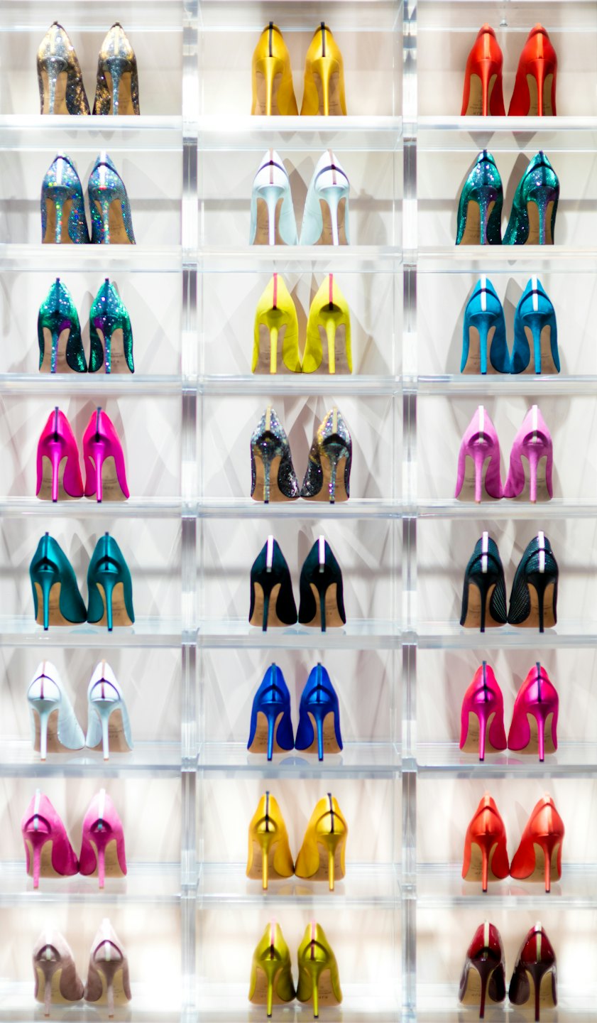 Scaffali con esposte varie scarpe col tacco alto colorate.