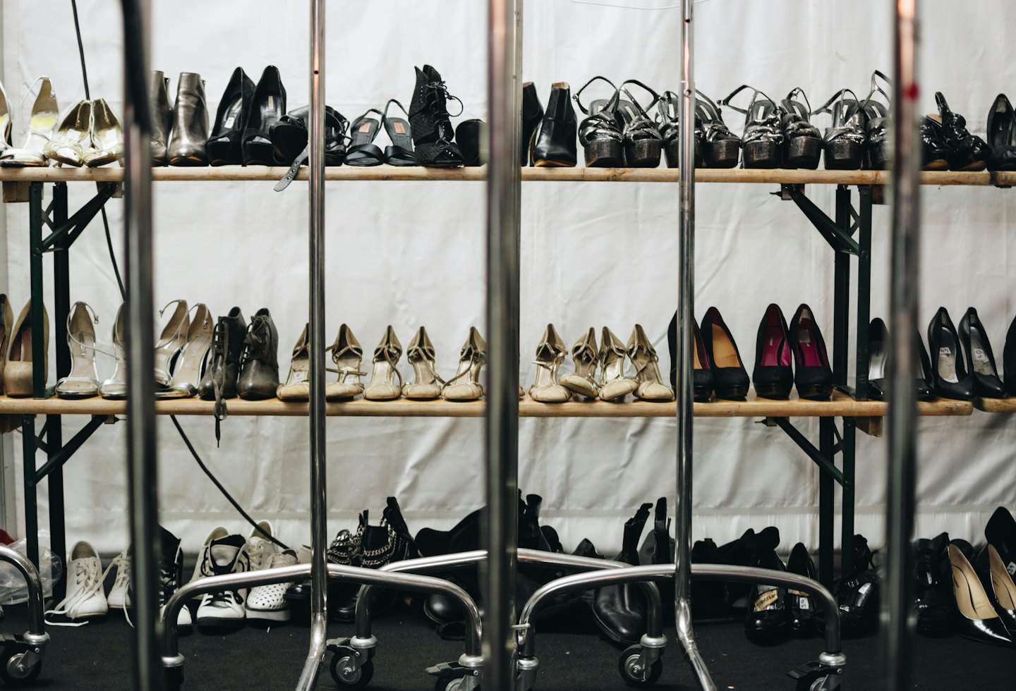 Assortimento di scarpe da donna esposte su scaffali di legno e a terra.
