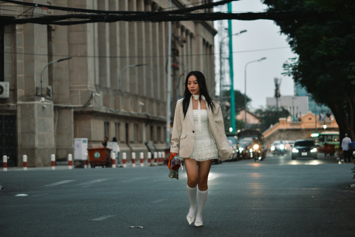 Donna con blazer beige cammina per strada in città.